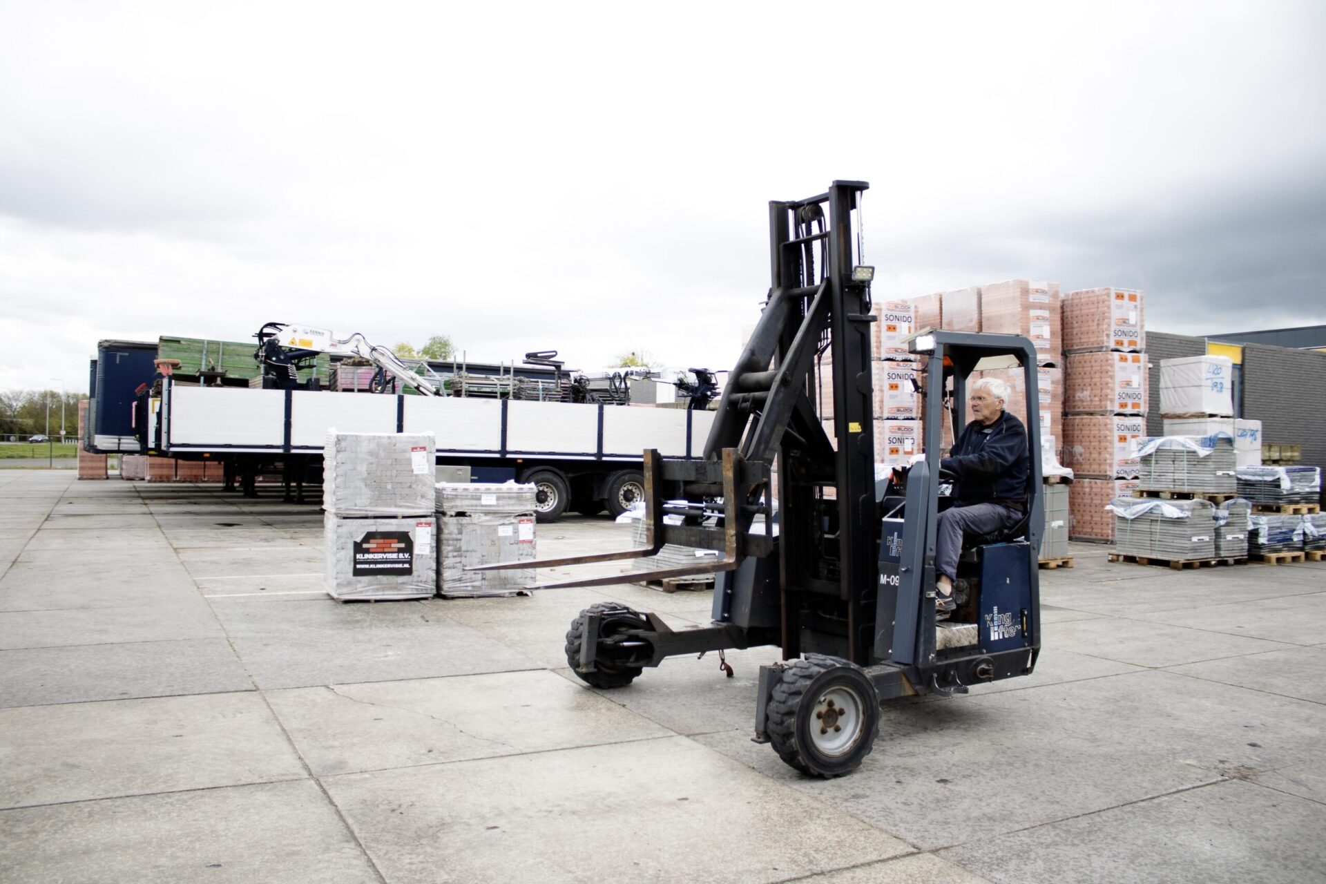 Kooiaap achter de vrachtwagen voor het lossen van bouwmateriaal op pallets