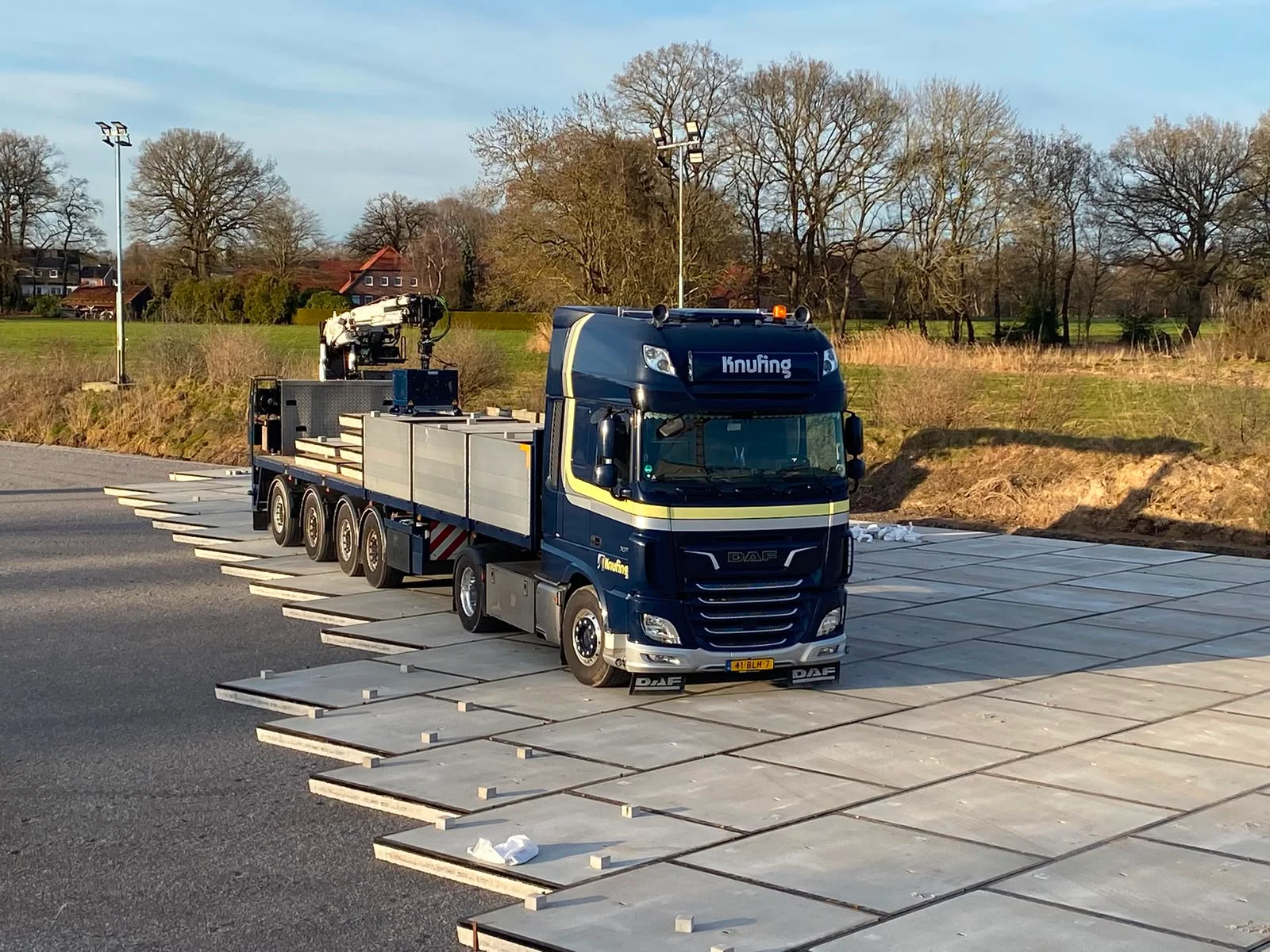 Autolaadkraan met zuignap die betonplaten gecontroleerd op de juiste plek legt